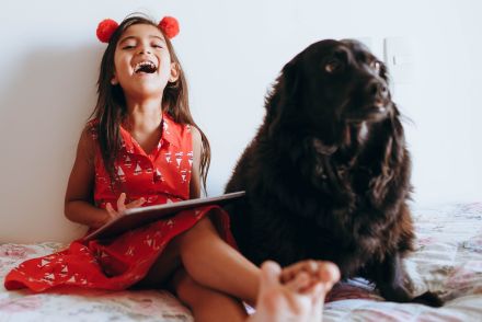 Happy Girl Sitting Beside Black Dog